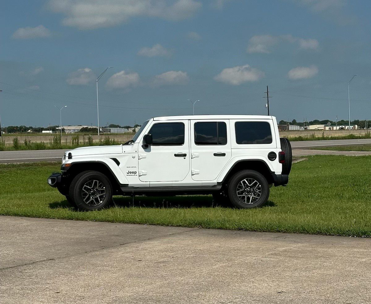 A white jeep is parked on the side of the road in a grassy field.