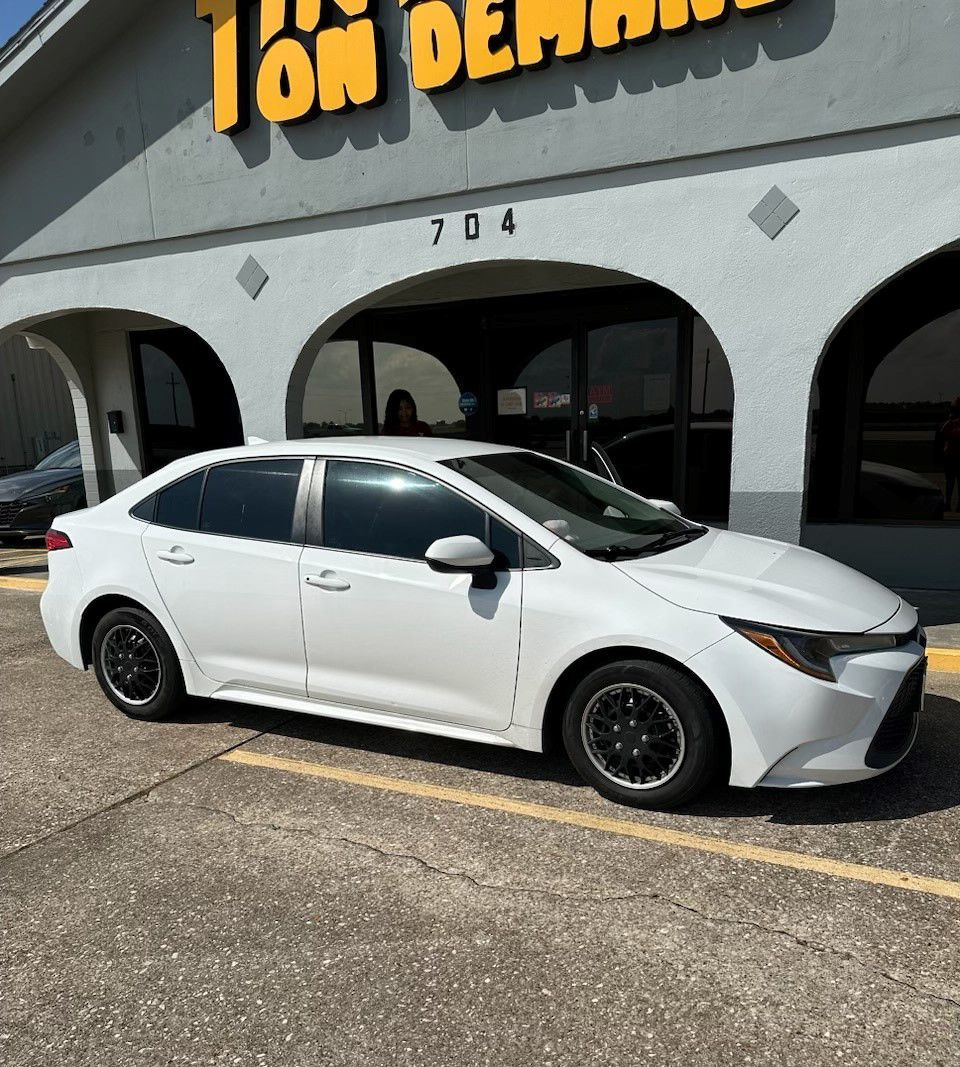 A white car is parked in front of a car dealership.