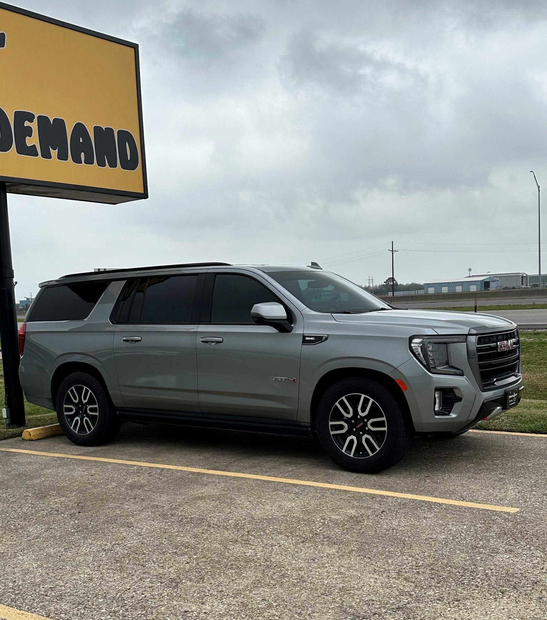 A silver suv is parked in a parking lot under a yellow sign.