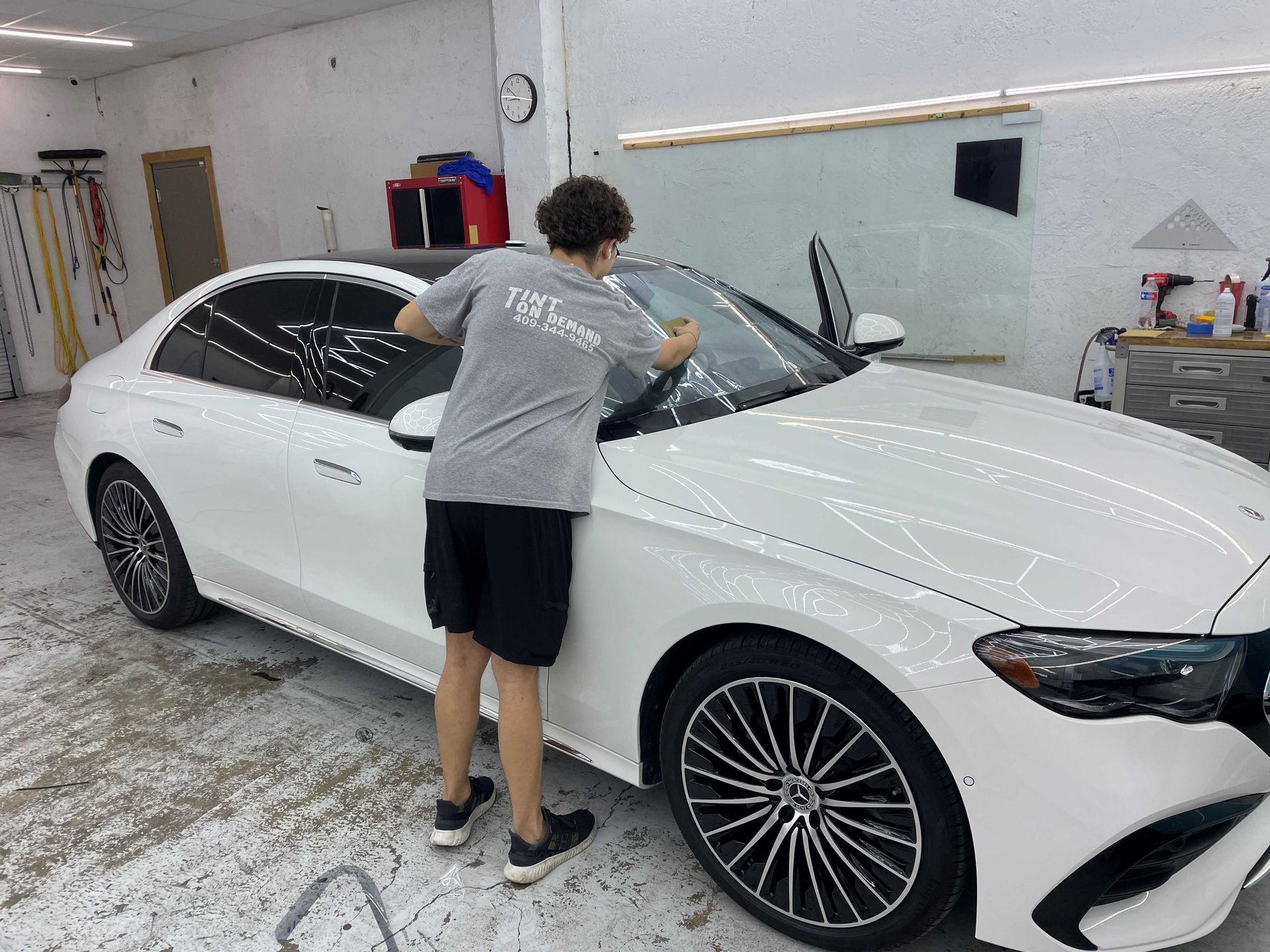 A man is standing next to a white car in a garage.