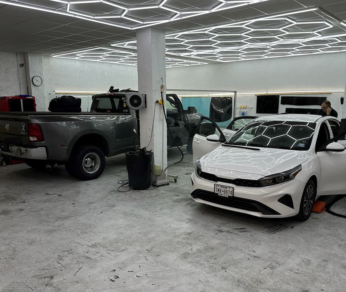 A white car is parked next to a gray truck in a garage.