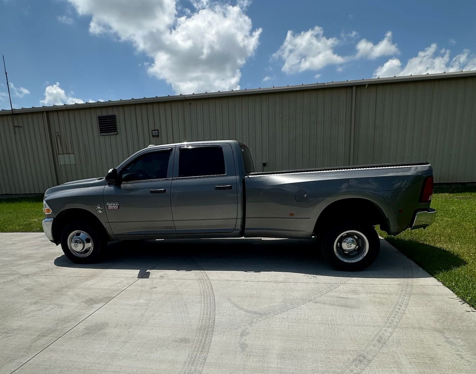 A gray truck is parked in a driveway in front of a building.
