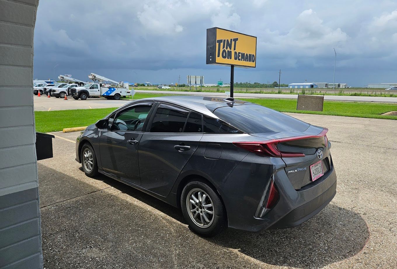 A gray car is parked in a parking lot next to a building.