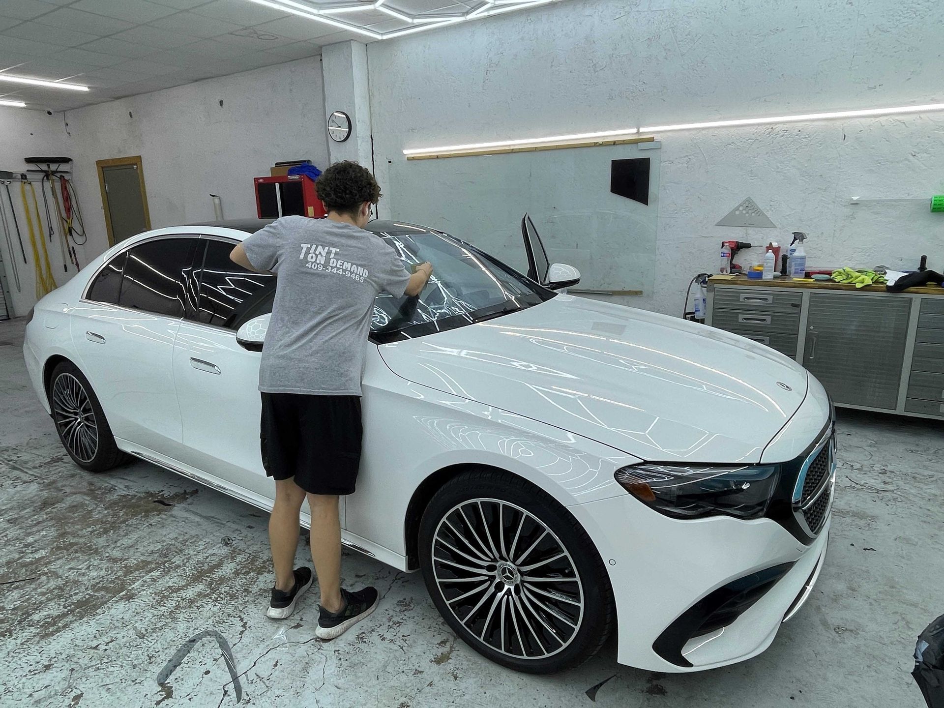 A man is standing next to a white car in a garage.