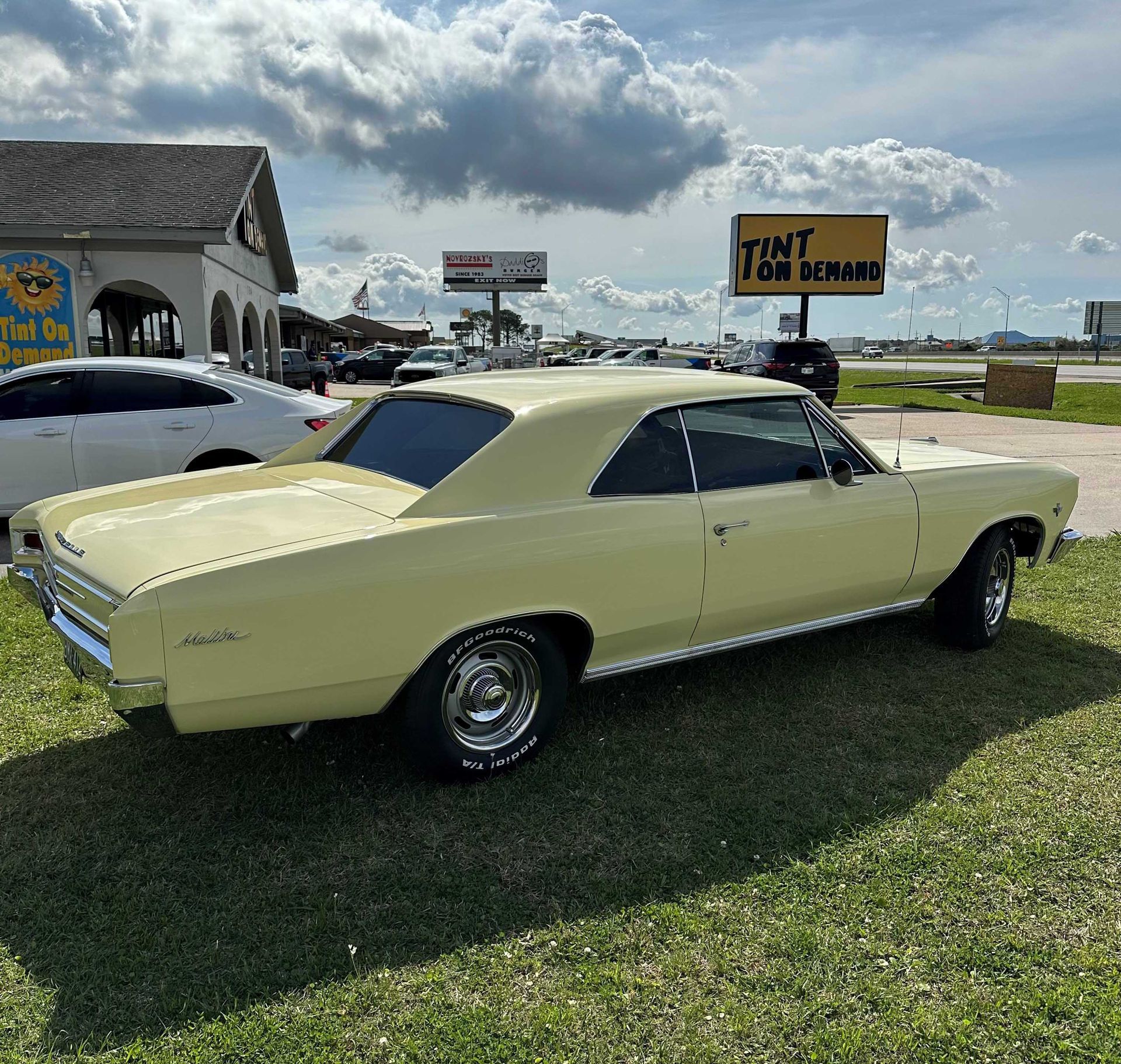 A yellow car is parked in front of a tint tow service sign