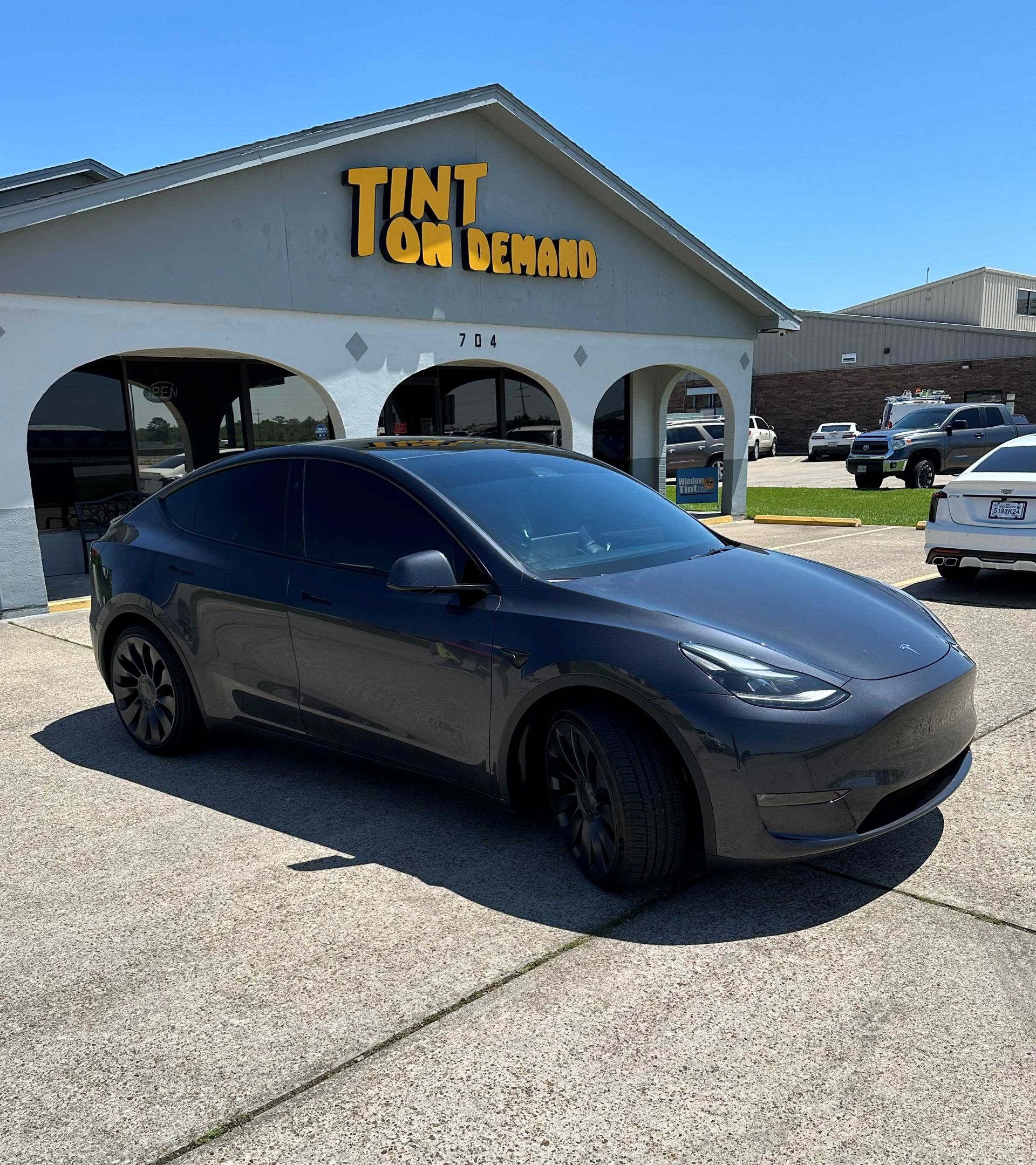 A car is parked in front of a building that says tint on it.
