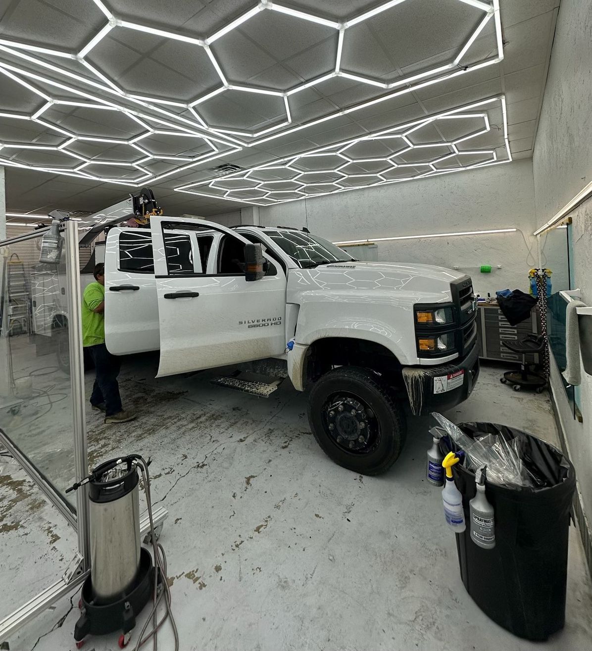A white truck is parked in a garage with its doors open.