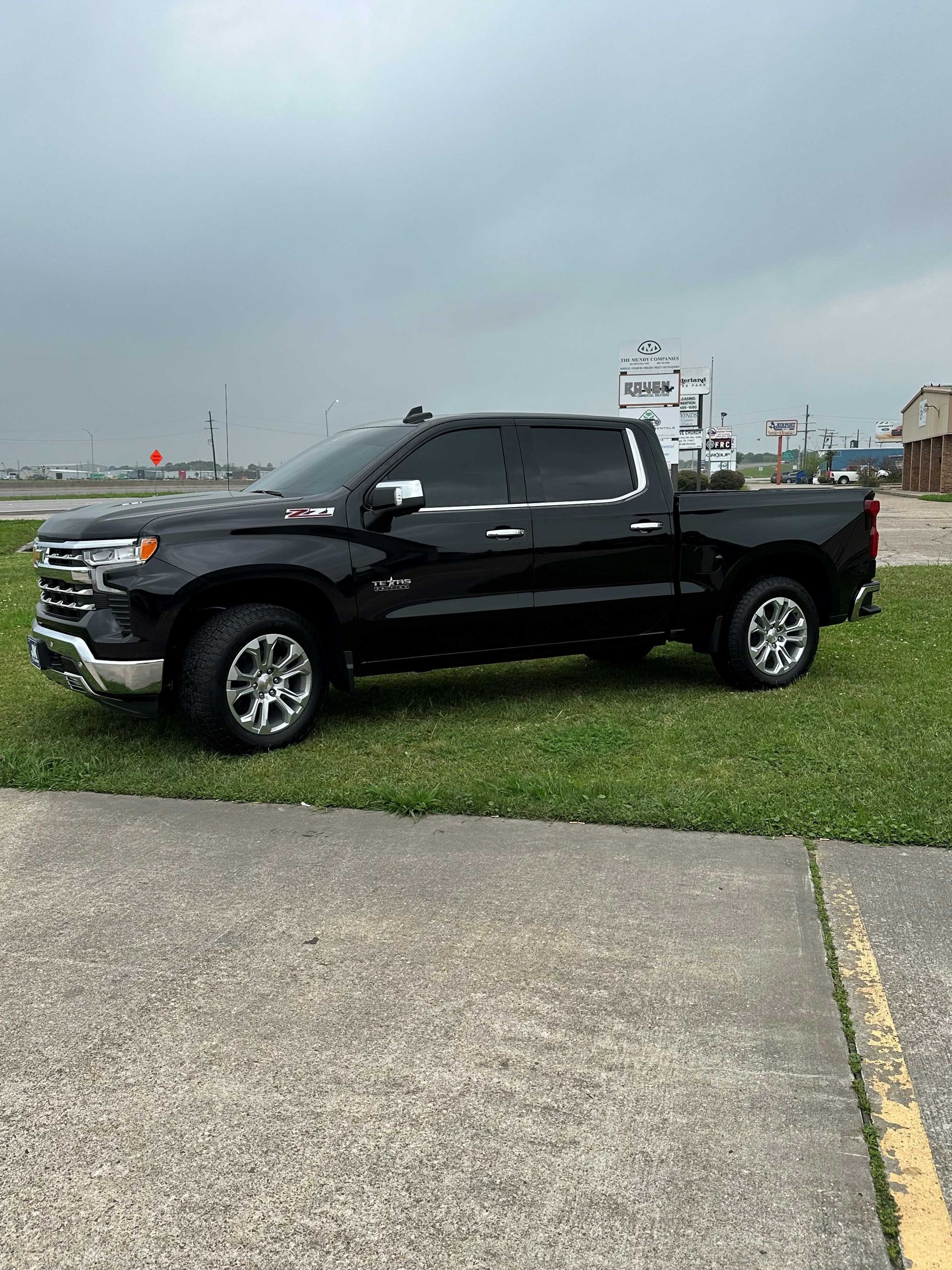 A black pickup truck is parked in a grassy field.