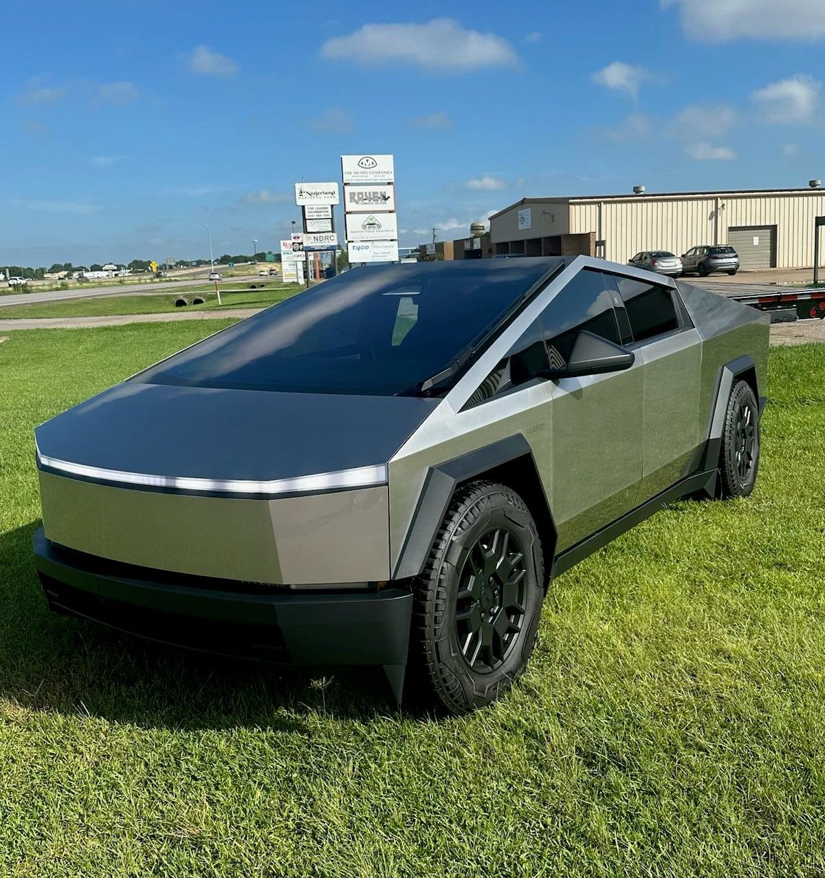 A tesla cybertruck is parked in a grassy field