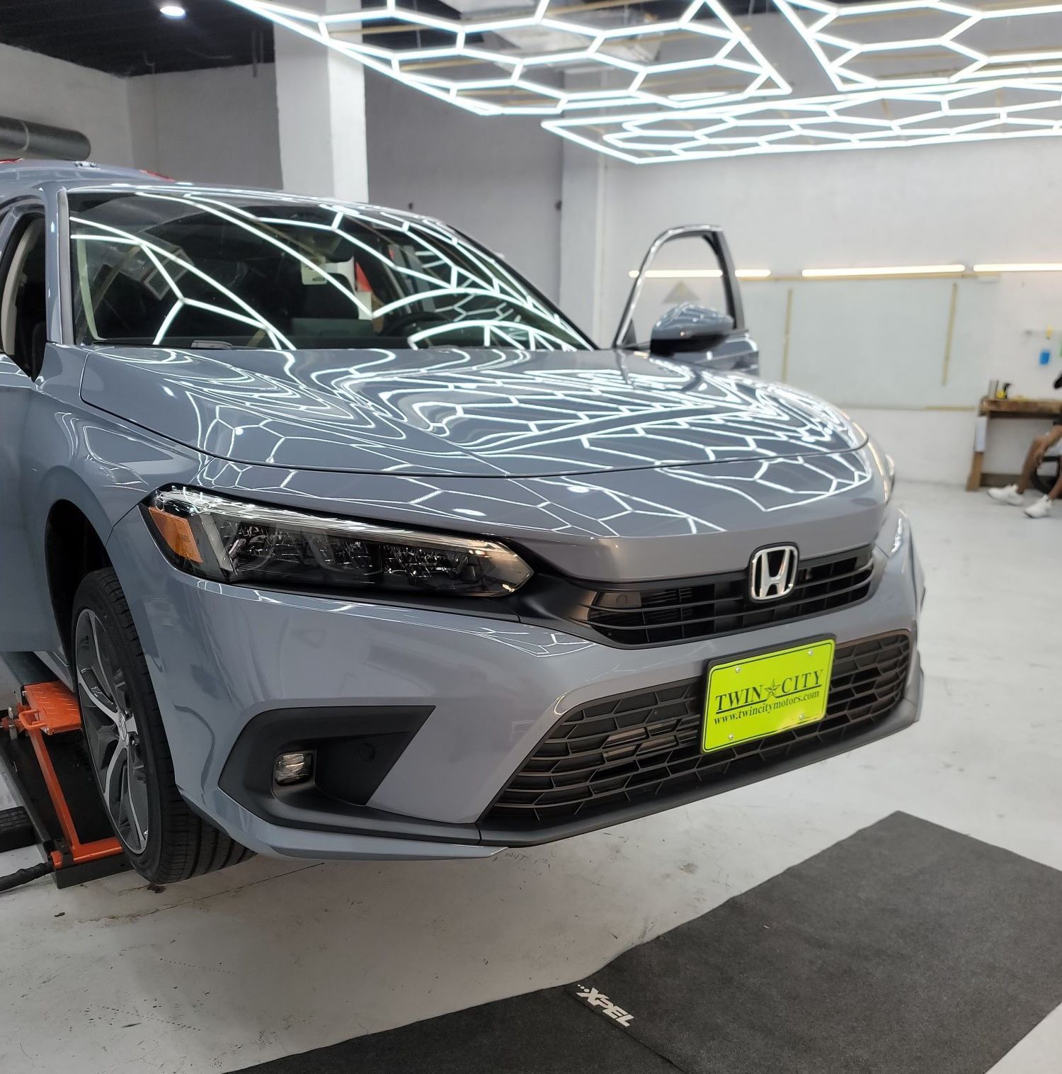 A gray honda car is parked on a lift in a garage