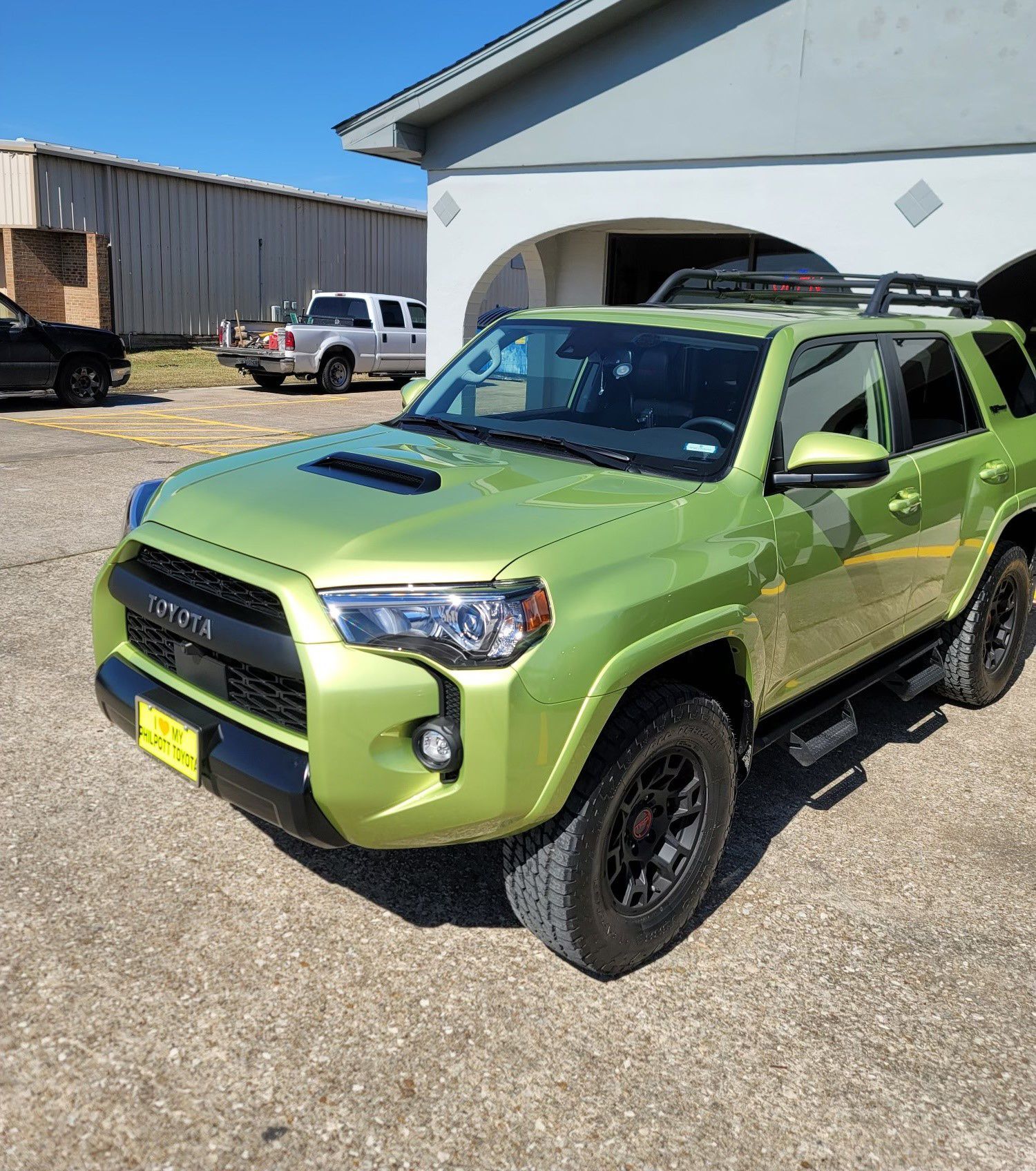 A green toyota 4runner is parked in front of a building.