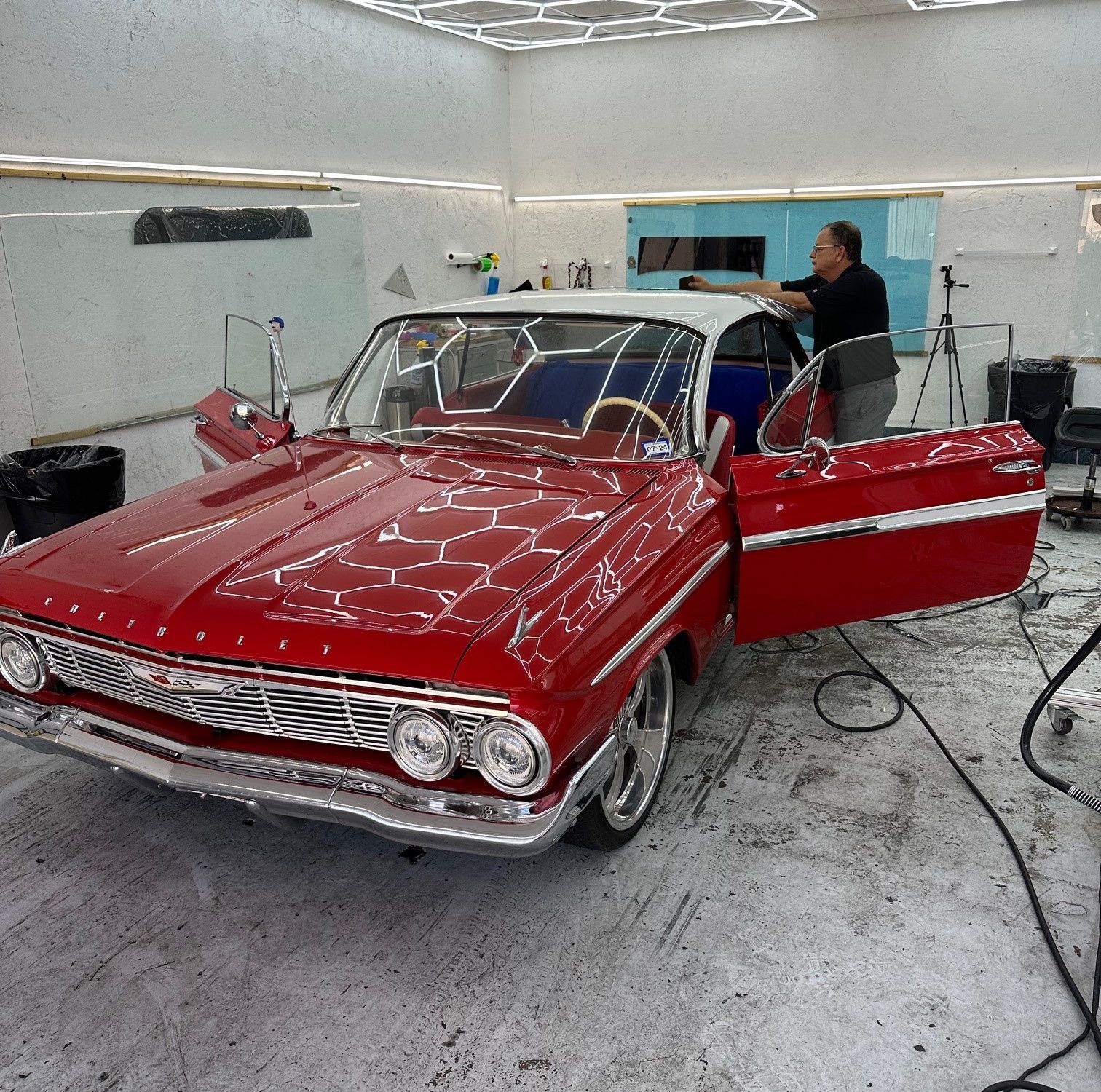A man is working on a red car in a garage