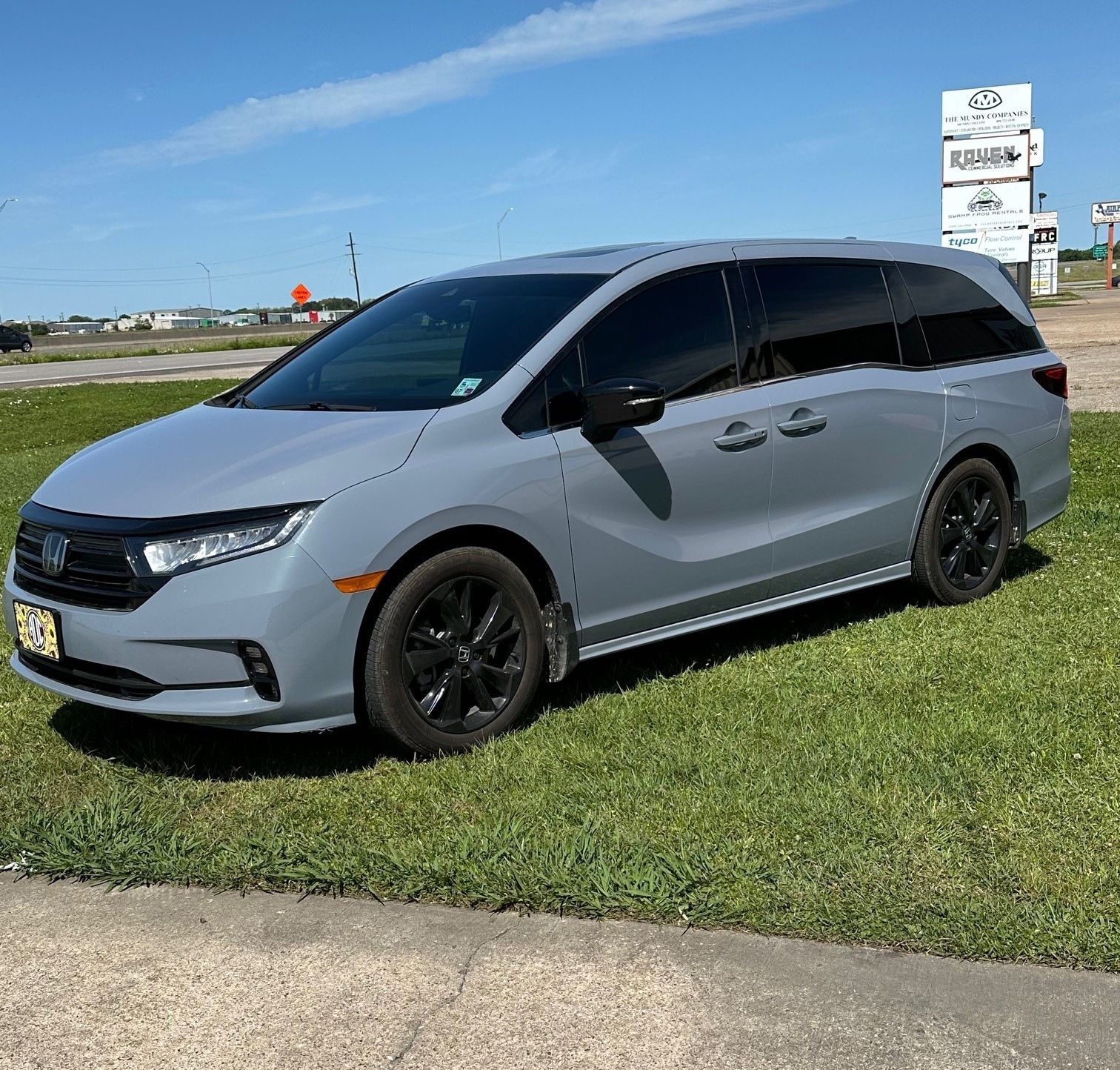 A gray minivan is parked in a grassy field
