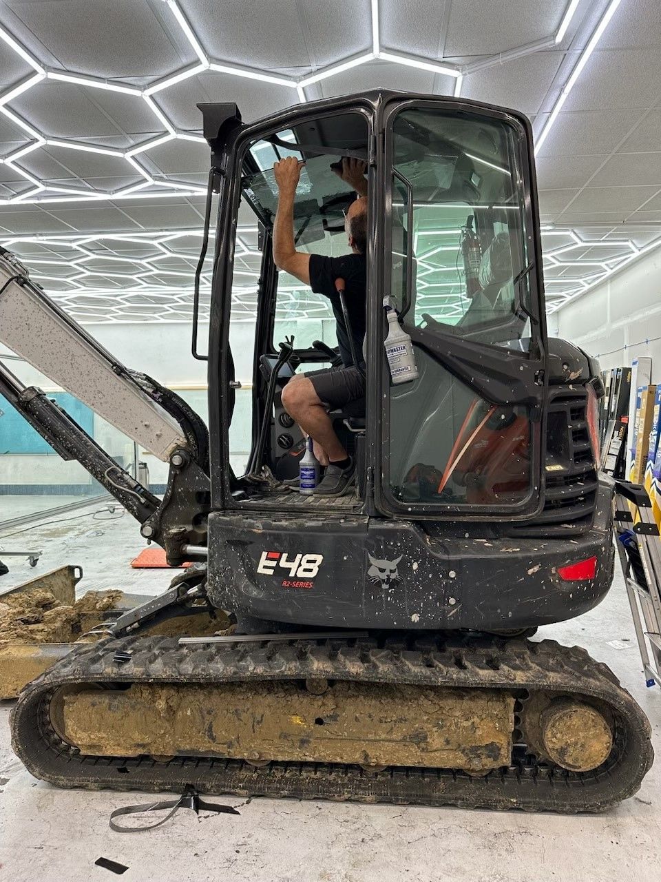 A man is sitting in the cab of a small excavator.