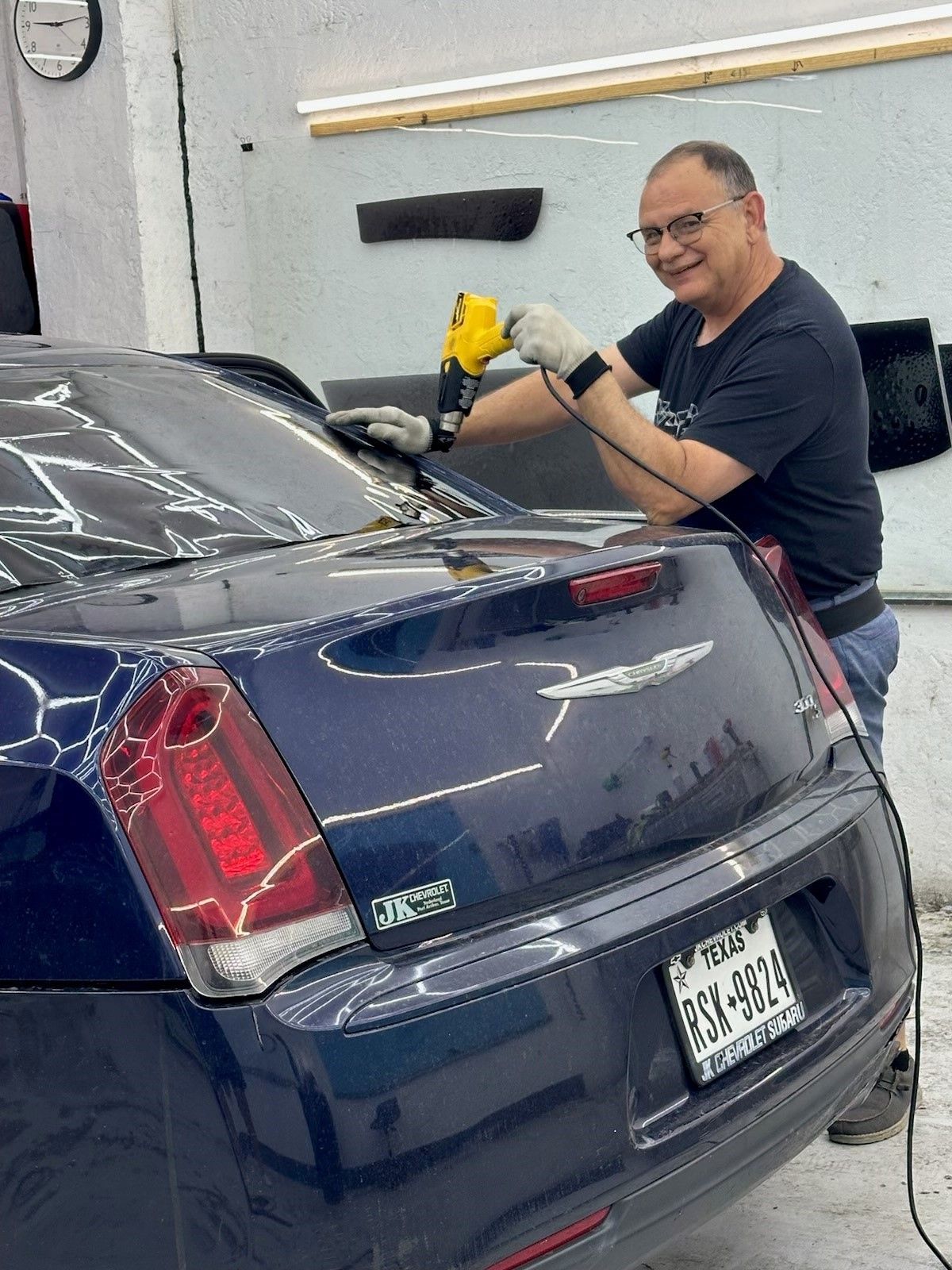 A man is working on a blue car in a garage.