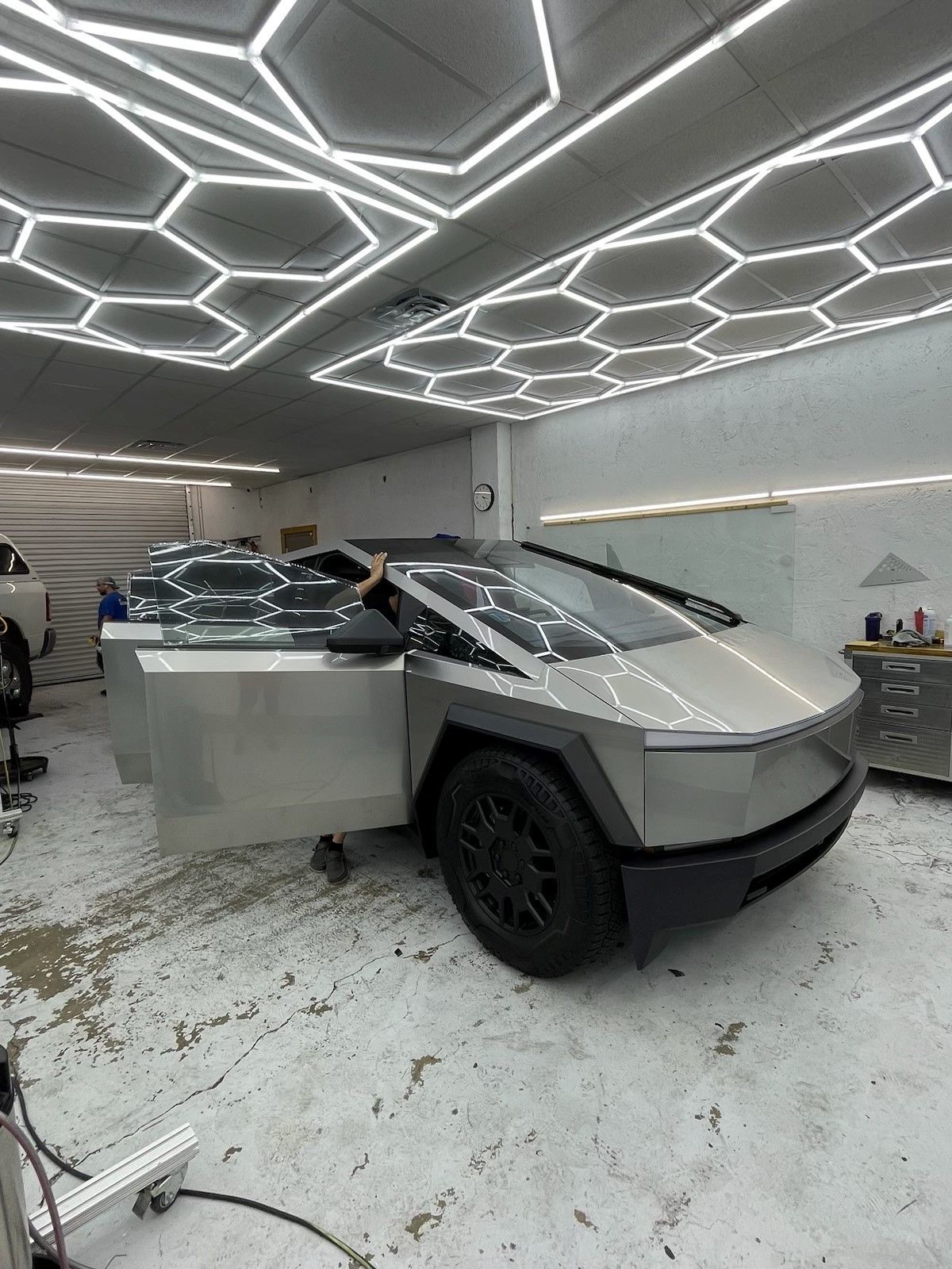 A tesla cybertruck is parked in a garage with its doors open.