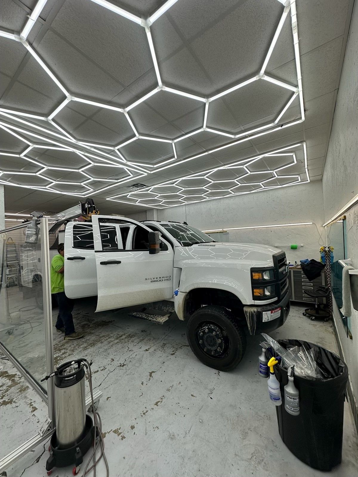A white truck is parked in a garage with its doors open.