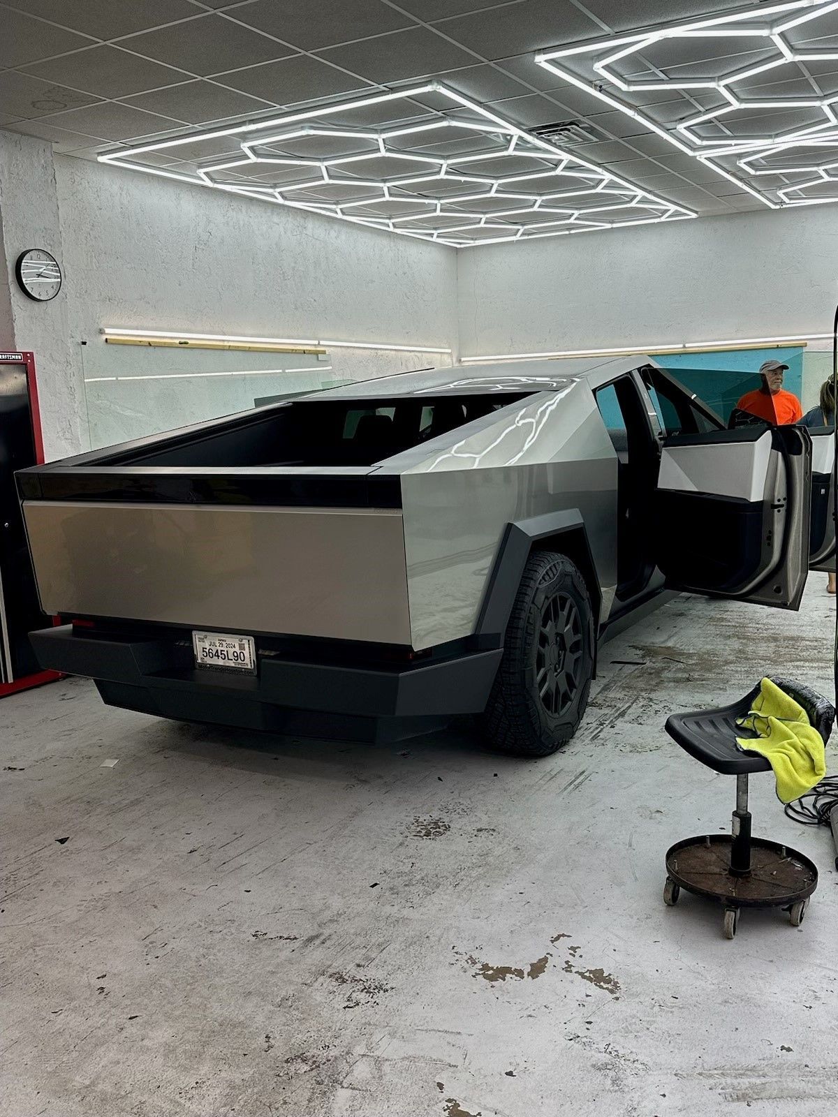 A tesla cybertruck is parked in a garage with its doors open.