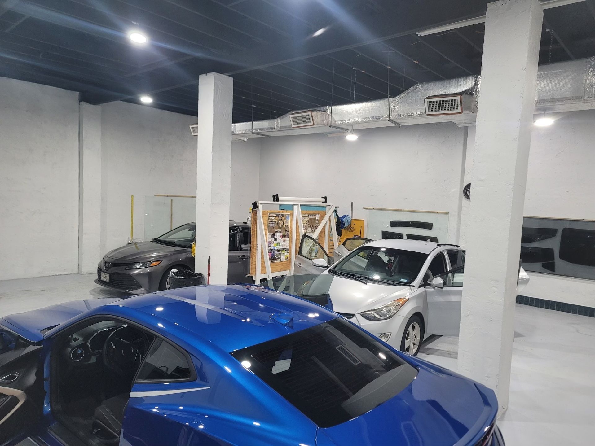 A blue car is parked in a garage with other cars.