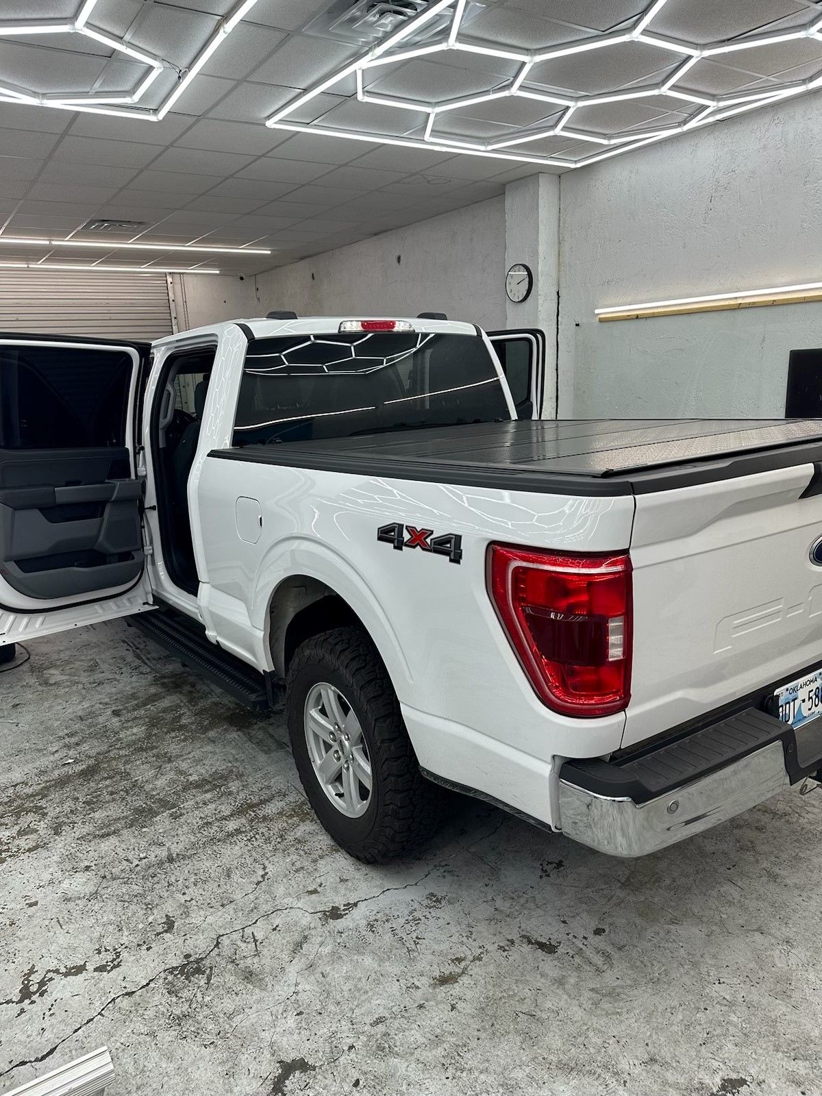 A white pickup truck is parked in a garage with the door open.