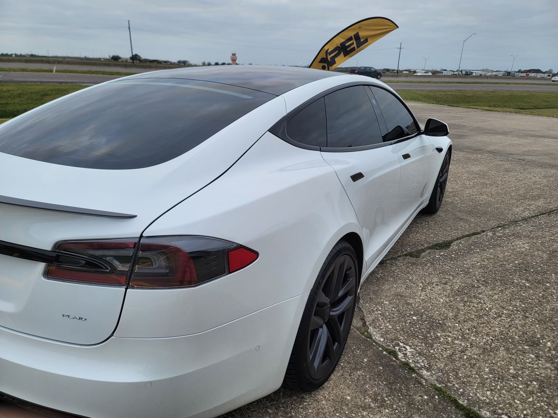 A white tesla model s is parked on the side of the road.