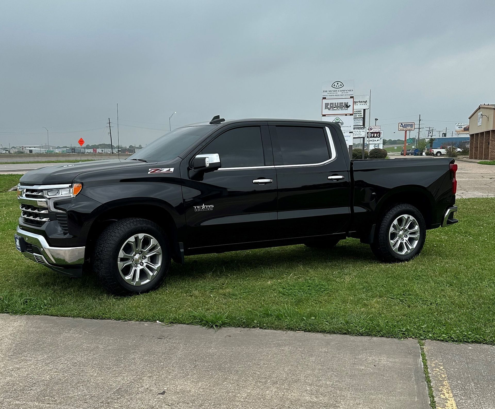 A black truck is parked in a grassy field.