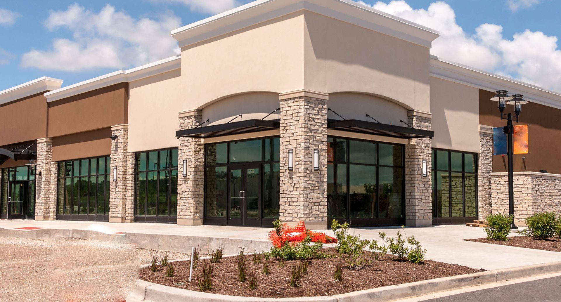 A large commercial building with a lot of windows and a parking lot in front of it.