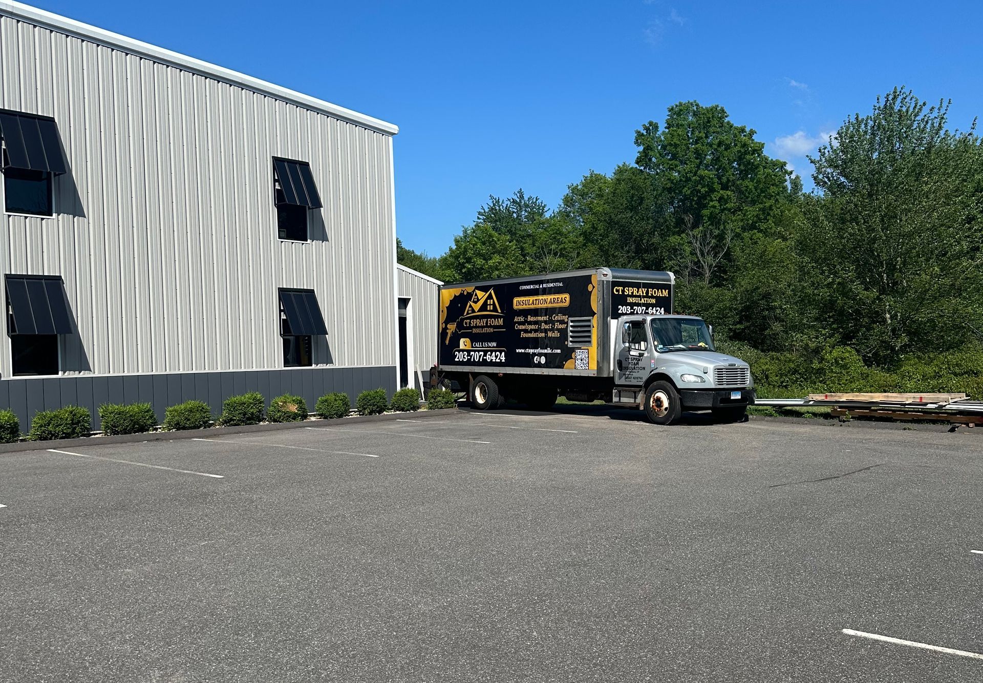 Truck parked next to a modern building with black accents. Sunny day.