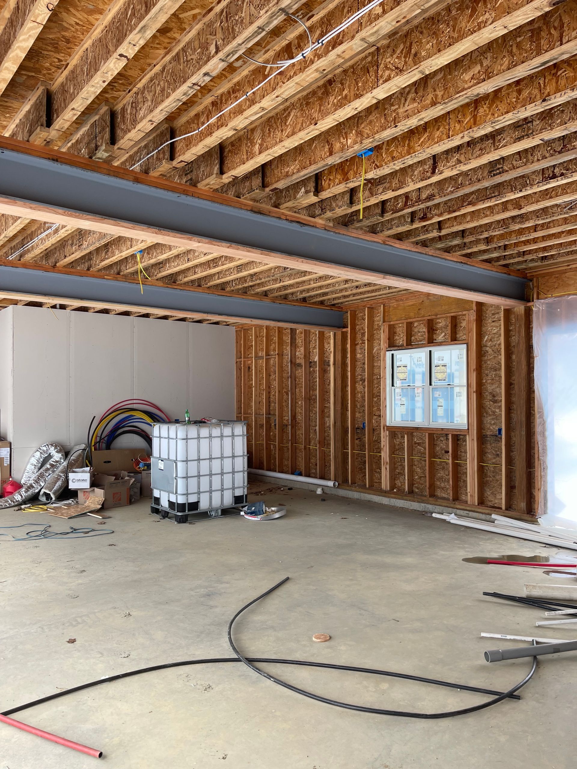 Interior of a building under construction, showing wooden framing, exposed beams, and concrete floor.