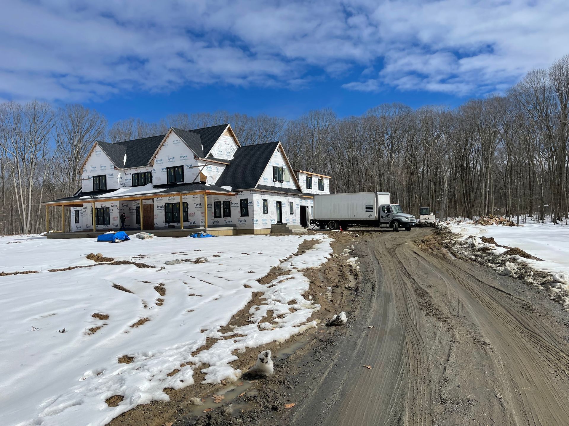 House under construction in a snowy setting with a delivery truck.