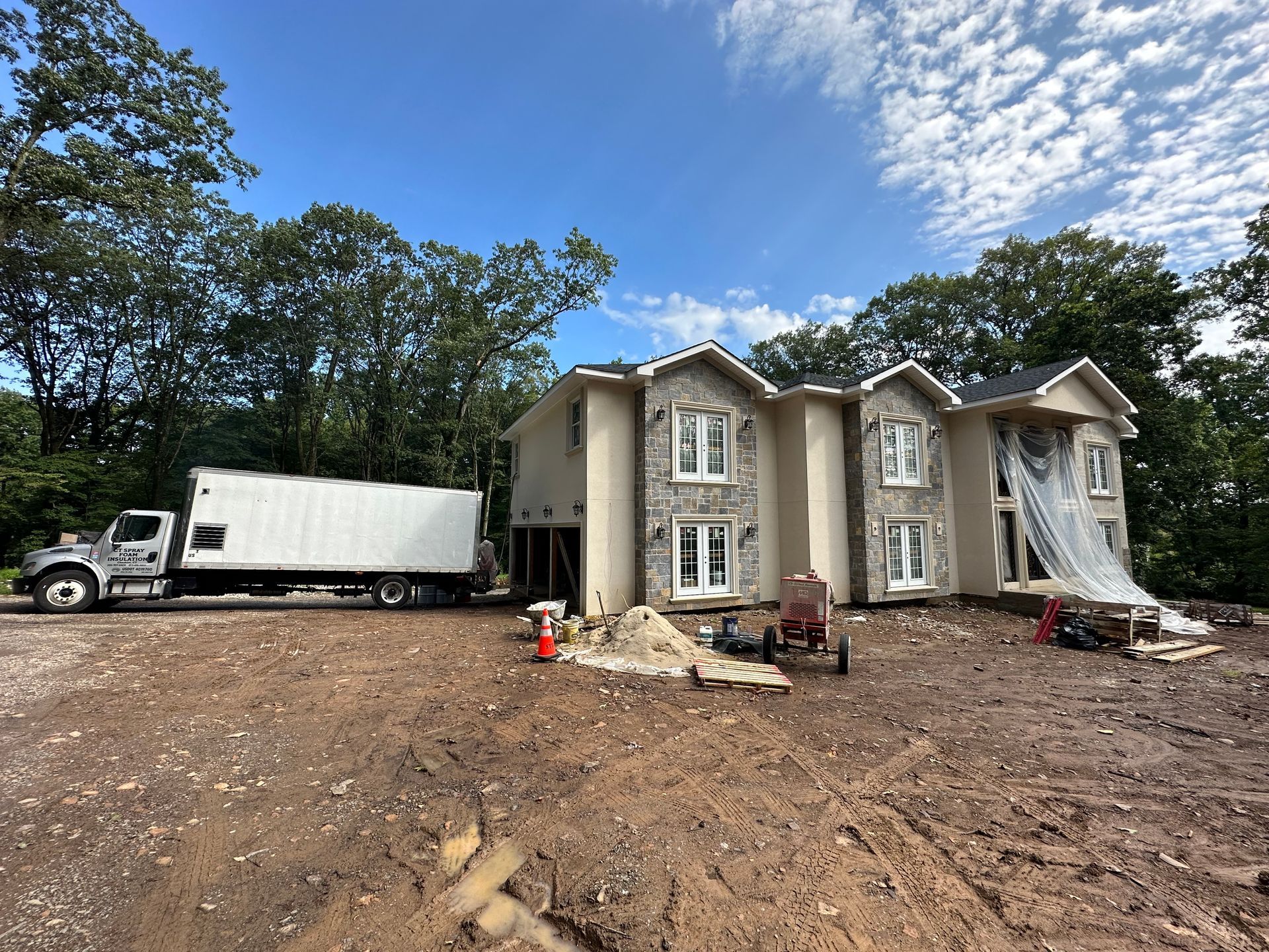 A truck parked next to a house under construction; cloudy blue sky in the background.