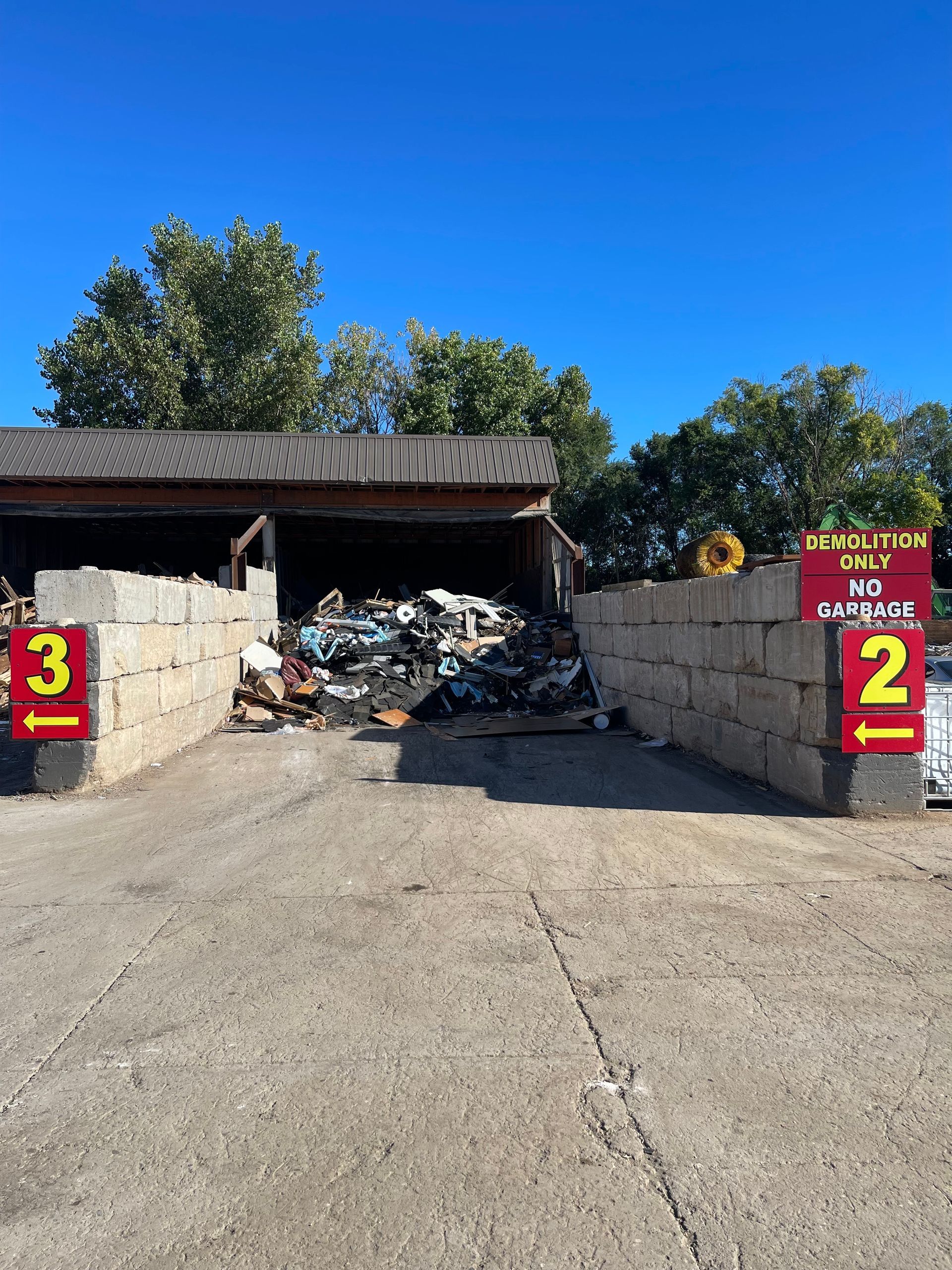 A pile of garbage is sitting in front of a building with a sign that says demolition only no garbage.
