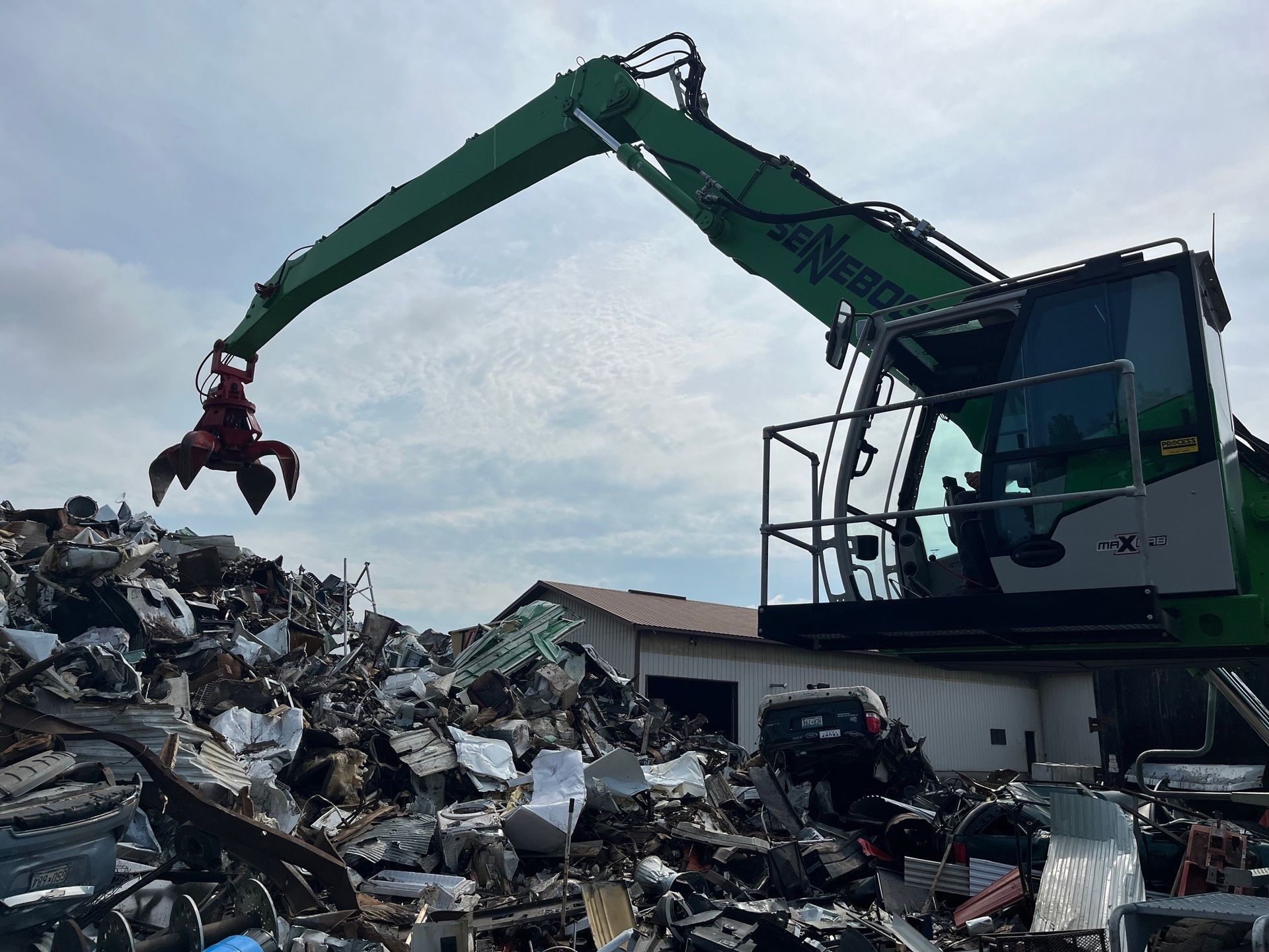 A green excavator is working on a pile of scrap metal.