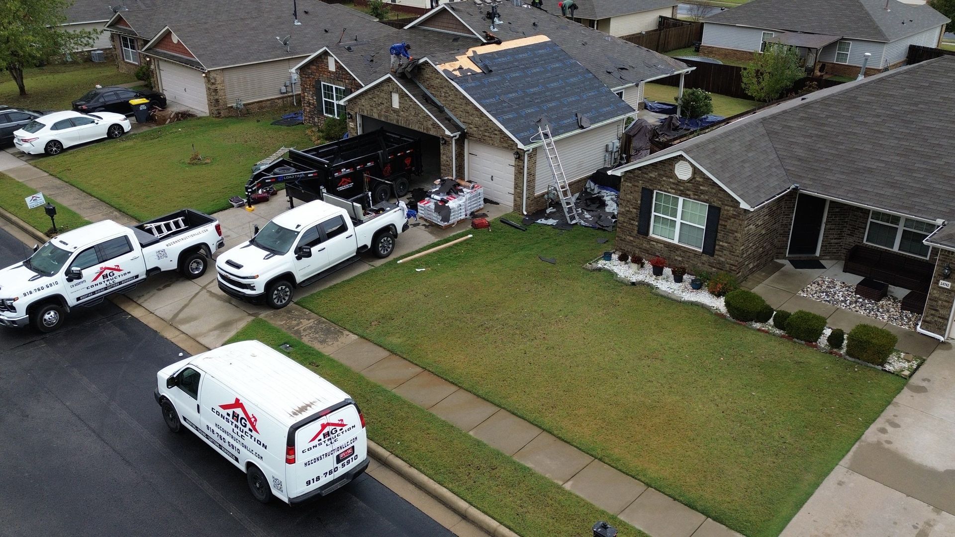 Aerial view of roofers and trucks at a residential house.