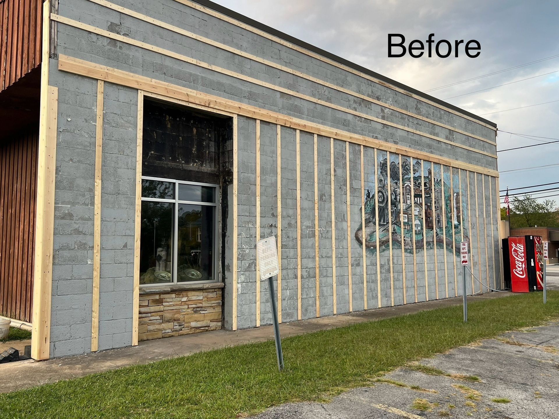 Building exterior before renovation: gray walls with wooden frame. Mural on the right.