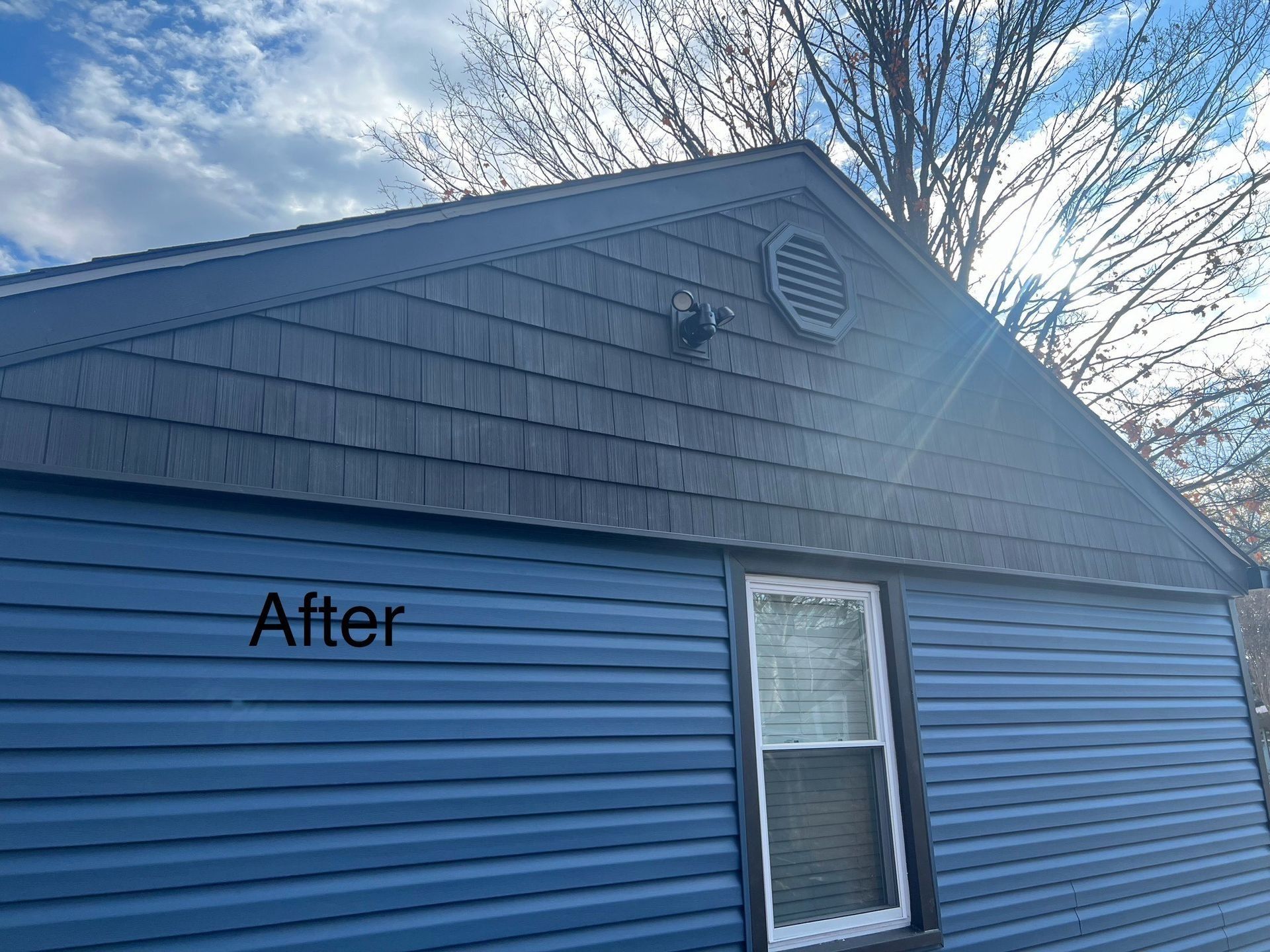 Blue house with dark gray siding and a window, under a bright sky, labeled 