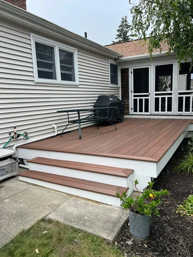 A house with a screened in porch and a wooden deck.