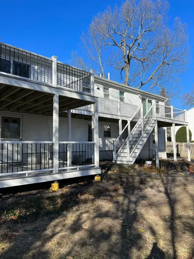 A white house with a large deck and stairs.