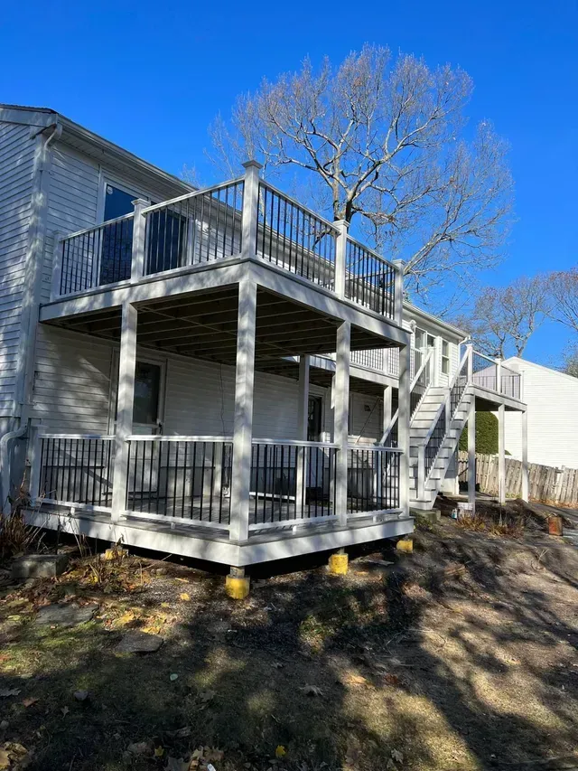 A white house with a large deck and stairs.