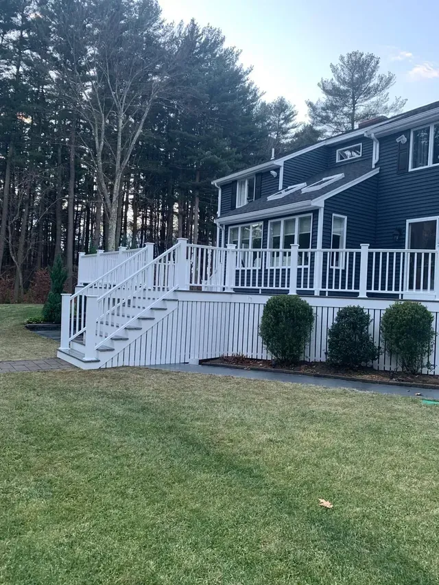 A large house with a large deck and stairs in the backyard.