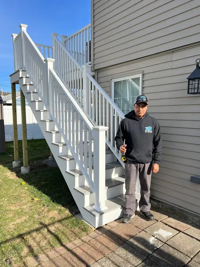 A man is standing next to a set of stairs in front of a house.
