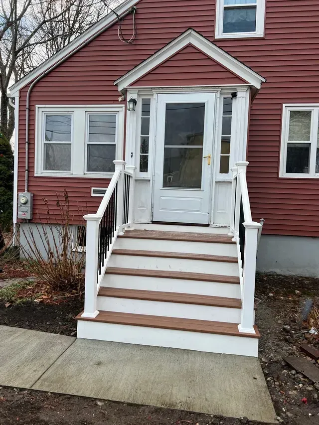 A red house with a white porch and stairs.
