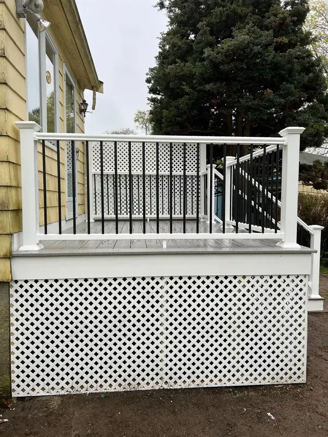 A white deck with a black railing and a lattice fence.
