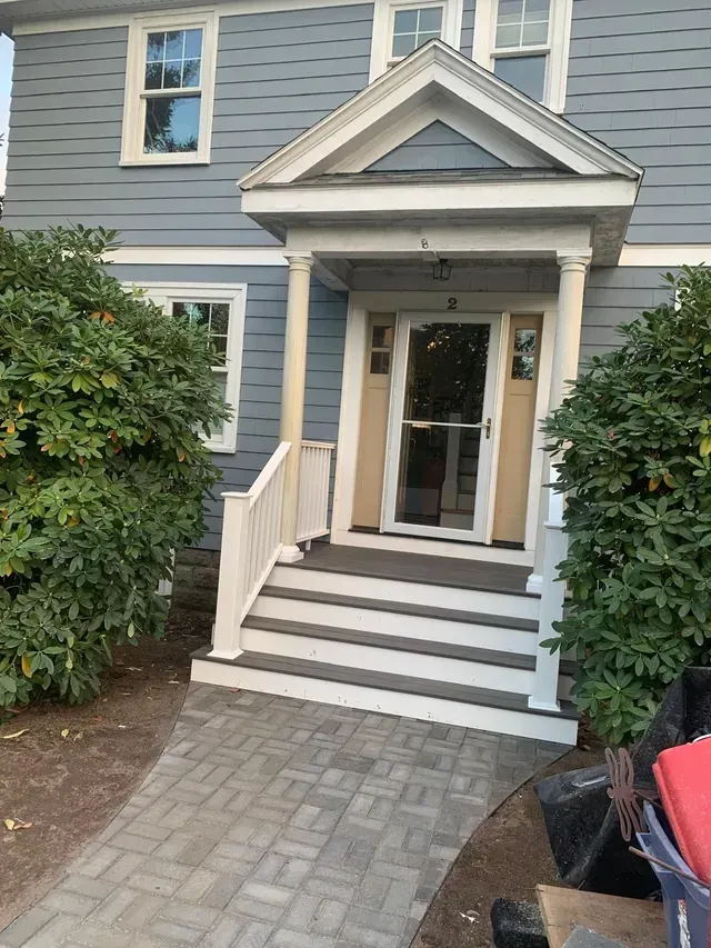 A blue house with a porch and stairs leading up to it.