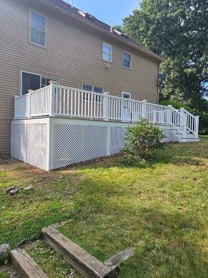 A large white deck is in the backyard of a house.