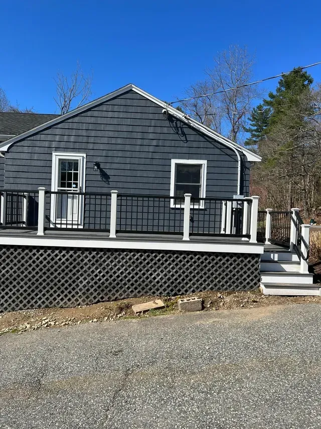 A small house with a large deck and stairs.