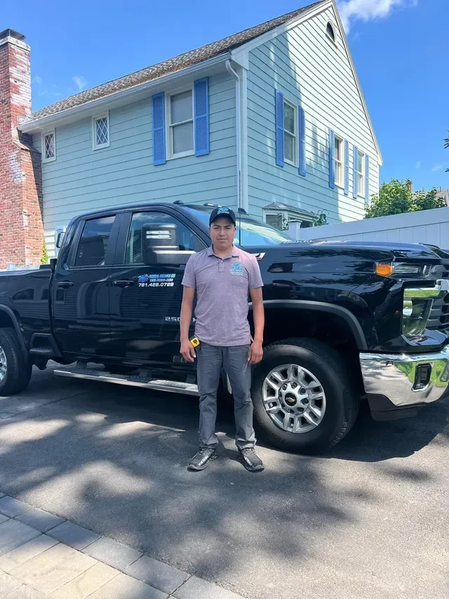 A man is standing in front of a black truck.