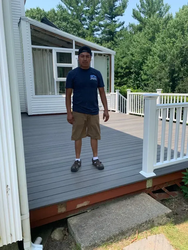 A man is standing on a deck next to a house.