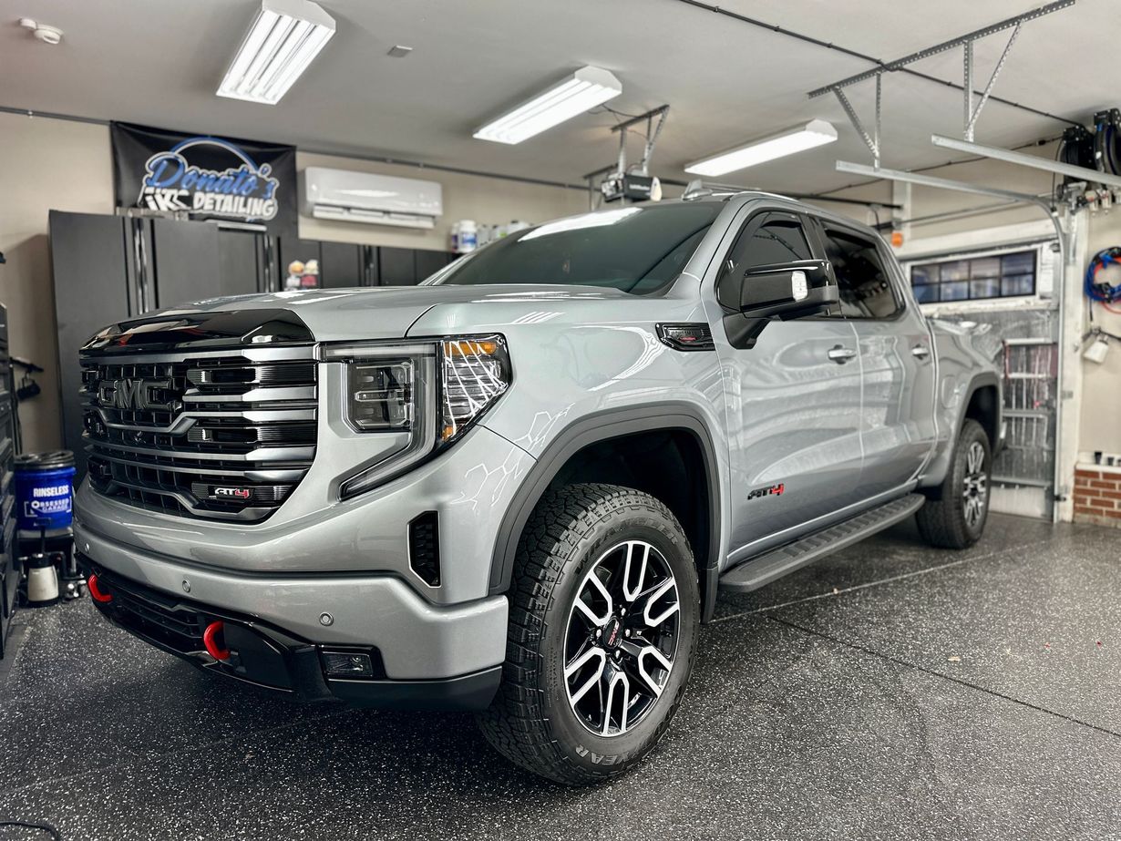 Gray GMC Sierra truck parked inside a well-lit garage with a black and white speckled floor.
