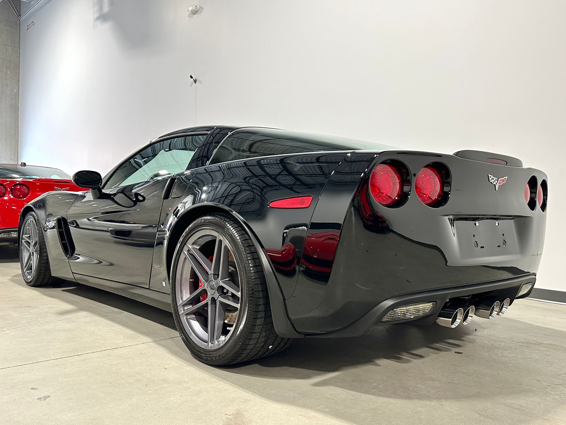 Black Corvette sports car, rear view, in a showroom.
